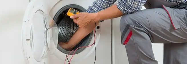 Dryer repair technician inspecting and repairing a clothes dryer in Chattanooga, TN