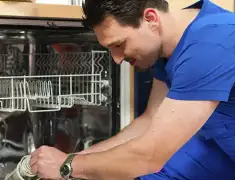 Dishwasher repair technician inspecting and servicing an open dishwasher in Chattanooga, TN