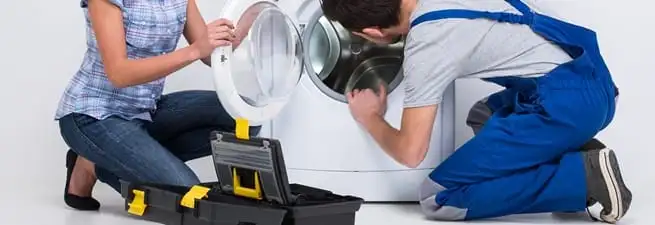 Washer repair technician inspecting a front-load washing machine with tools in Chattanooga, TN