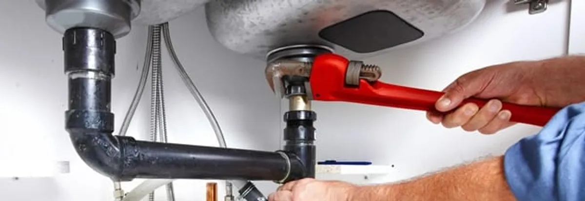 Garbage disposal repair technician tightening the sink drain and disposal connection in Chattanooga, TN