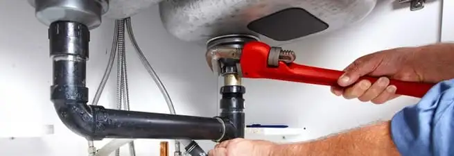 Garbage disposal repair technician tightening the sink drain and disposal connection in Chattanooga, TN