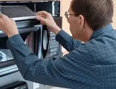 Appliance repair technician replacing a microwave vent filter in Chattanooga, TN