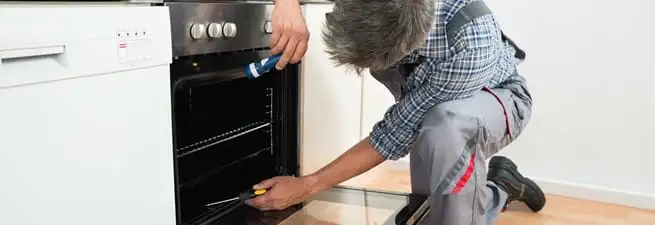 Oven repair technician inspecting and servicing an electric oven in Chattanooga, TN