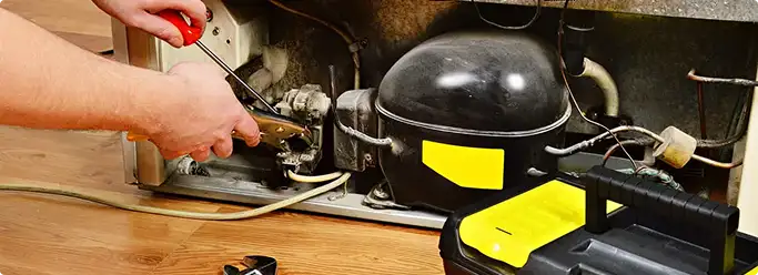 Refrigerator repair technician fixing the compressor and wiring in Chattanooga, TN