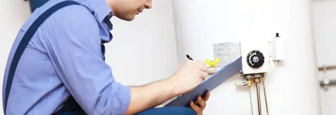 Water heater repair technician inspecting the unit and recording service notes in Chattanooga, TN